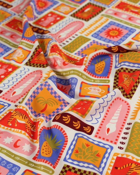 Colourful viscose fabric with a tile pattern featuring illustrations of tigers, seashells, suns, palm trees, fruit, pineapples, bananas and tropical imagery