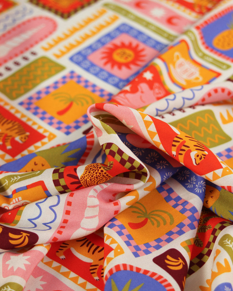 Colourful viscose fabric with a tile pattern featuring illustrations of tigers, seashells, suns, palm trees, fruit, pineapples, bananas and tropical imagery