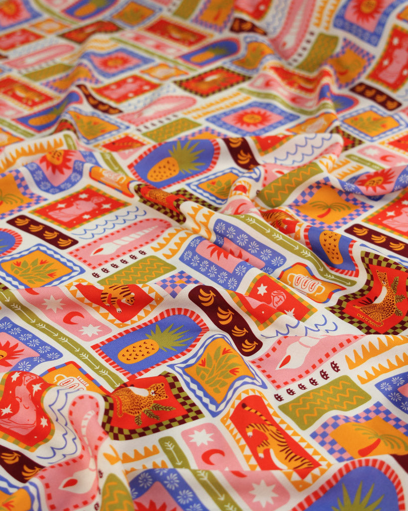 Colourful viscose fabric with a tile pattern featuring illustrations of tigers, seashells, suns, palm trees, fruit, pineapples, bananas and tropical imagery