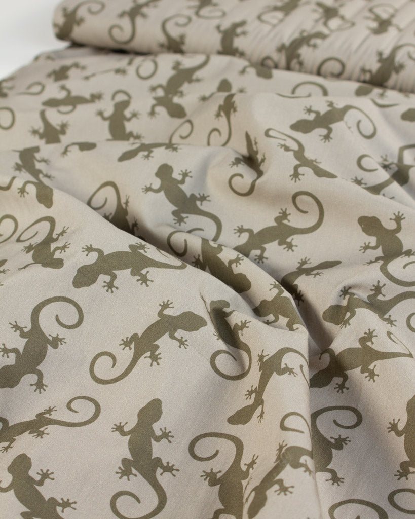 Cotton fabric with green gecko lizard pattern on beige background