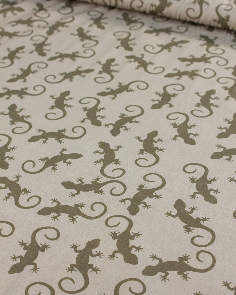 Cotton lawn fabric with a pattern of green lizards on a beige background