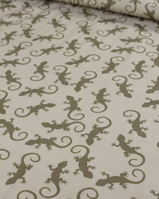 Cotton lawn fabric with a pattern of green lizards on a beige background