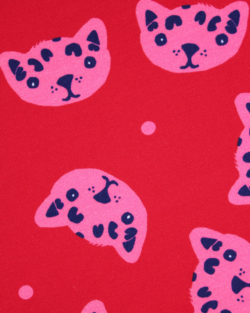 Pattern of pink and black cat faces on a red background on cotton jersey fabric