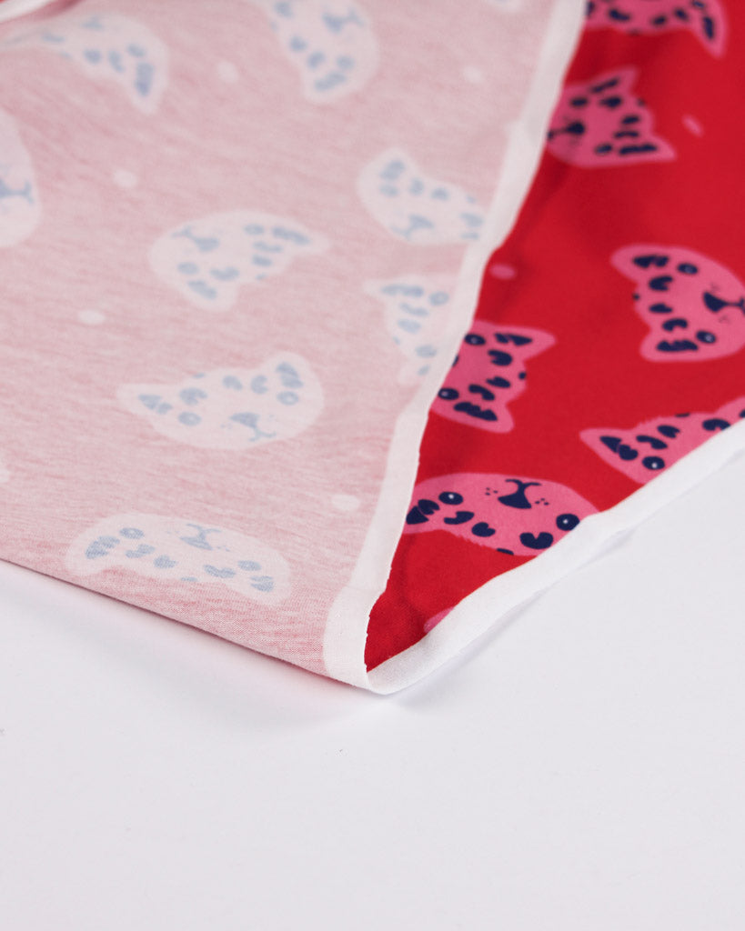 Close-up of cotton jersey fabric with a pink and red fabric with cheetah patterns on a white background