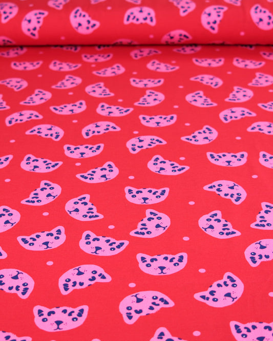 Cotton jersey fabric with pink and blue cat pattern on a red background