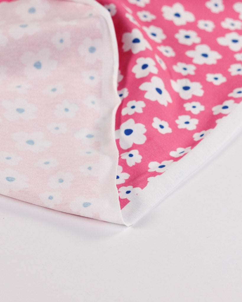 Close-up of pink cotton jersey fabric with white floral patterns on a white background