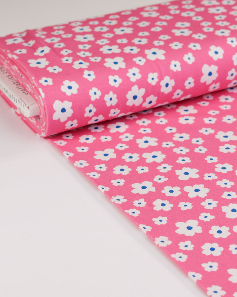 Pink cotton jersey fabric with white and blue floral pattern on a white background