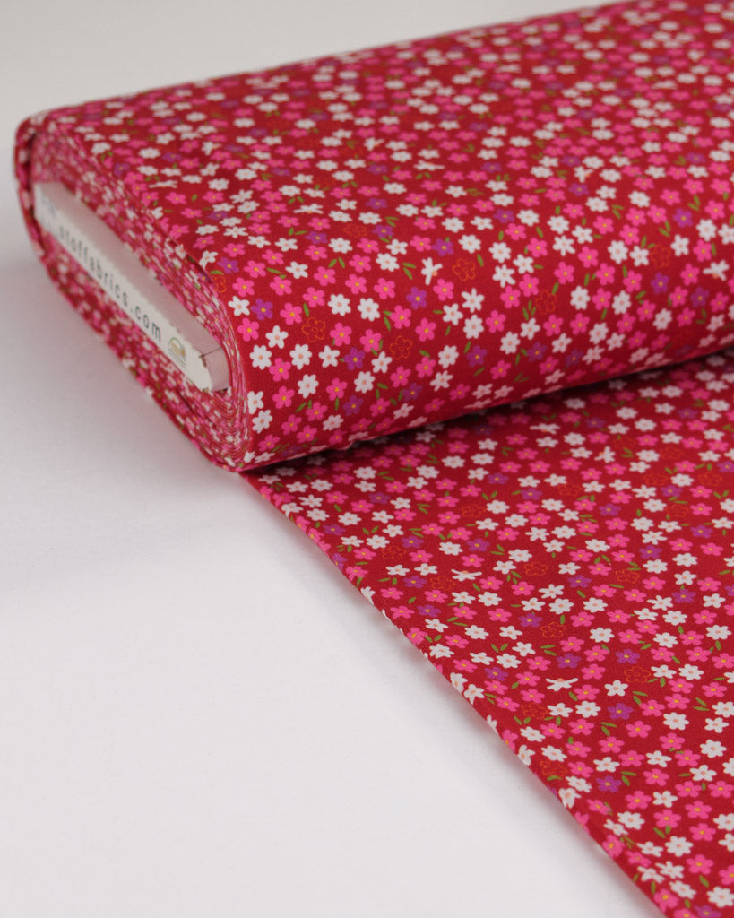 Roll of pink cotton jersey floral fabric on a white background