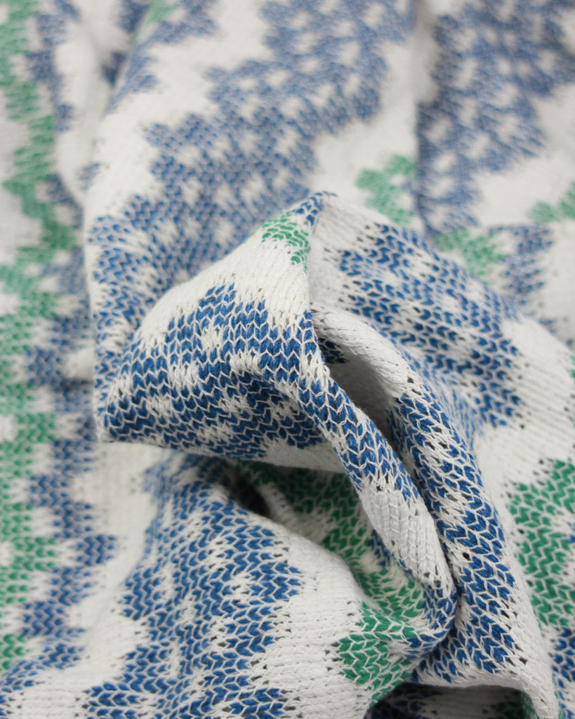 Close-up of patterned jersey knit fabric with blue, white, and green colors.
