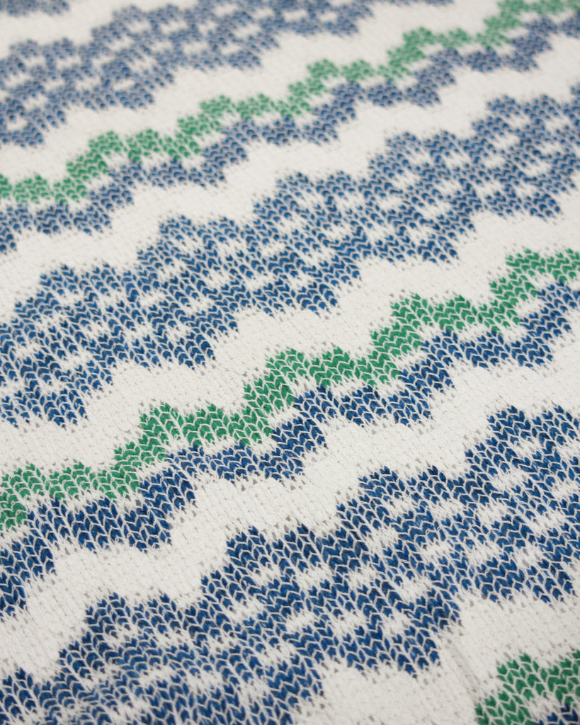 Patterned jersey knit fabric with blue and green design on a white background