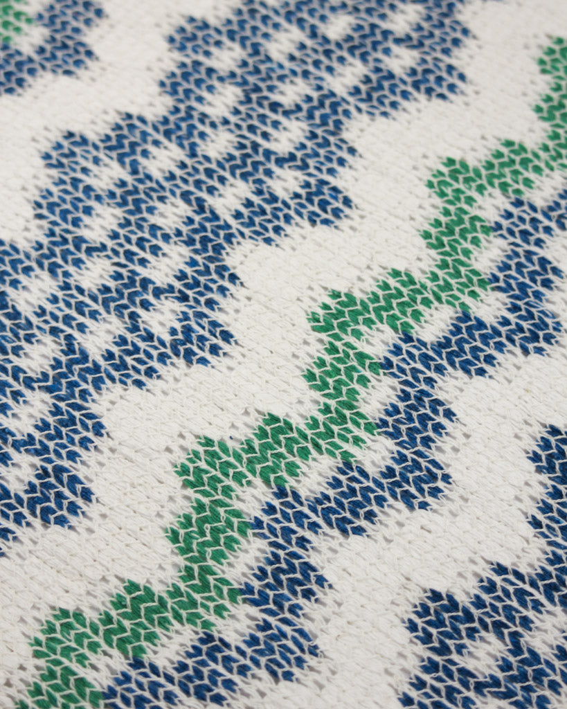 Close-up of a jersey knit fabric with blue and green pattern on a white background