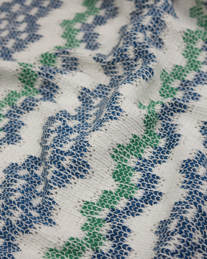 Close-up of knit fabric with blue and green pattern on a white background