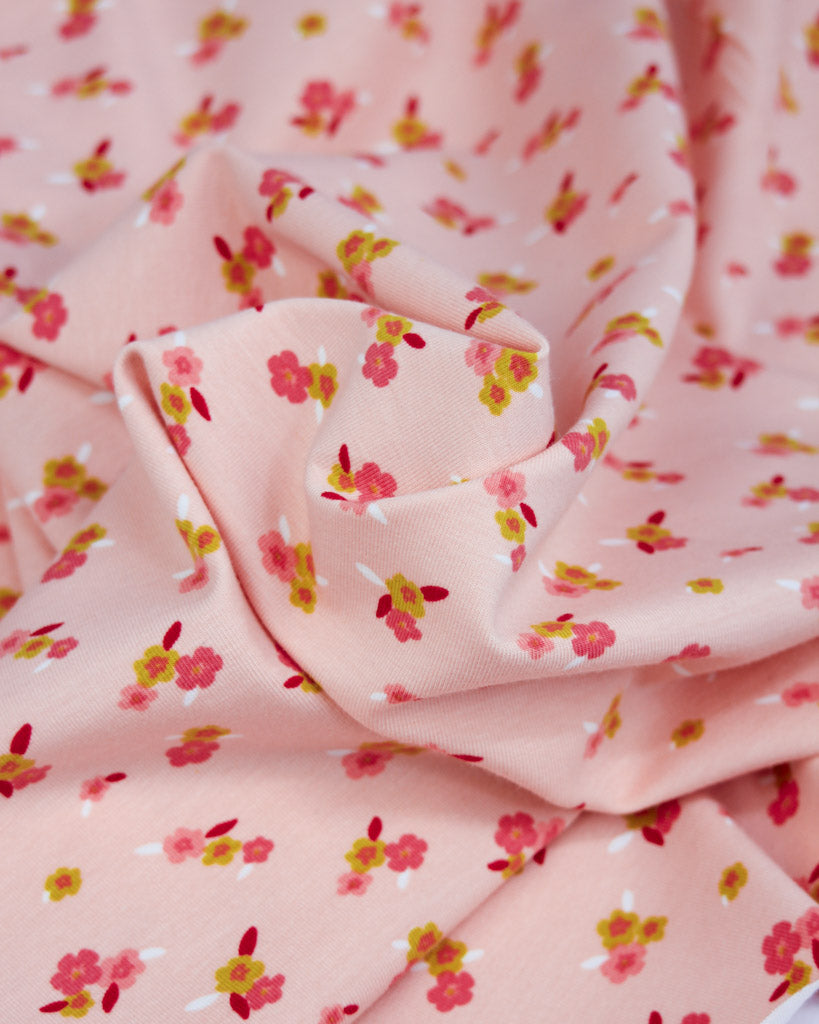 Pink floral cotton jersey fabric with small pink flowers on a pale pink background