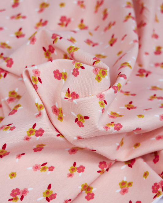 Pink floral cotton jersey fabric with small pink flowers on a pale pink background