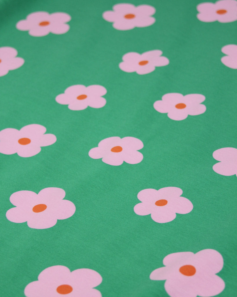 Pink flowers with orange centers on a green background on a cotton jersey fabric