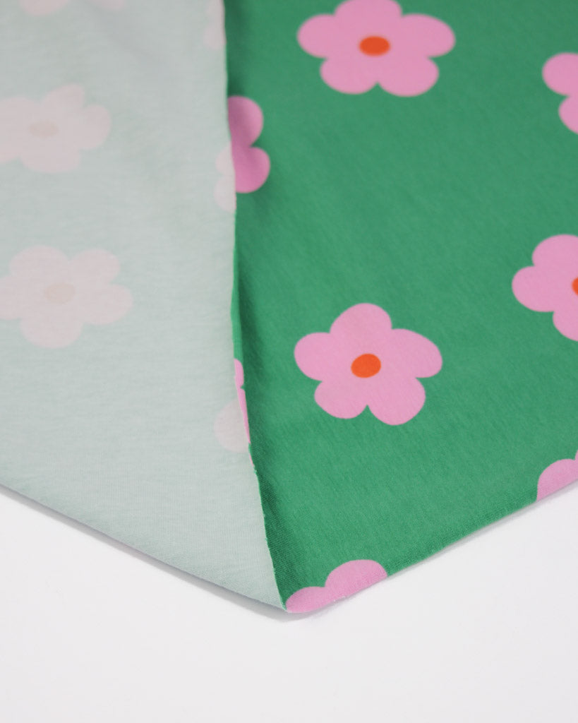 Cotton jersey fabric with pink flowers on a green background