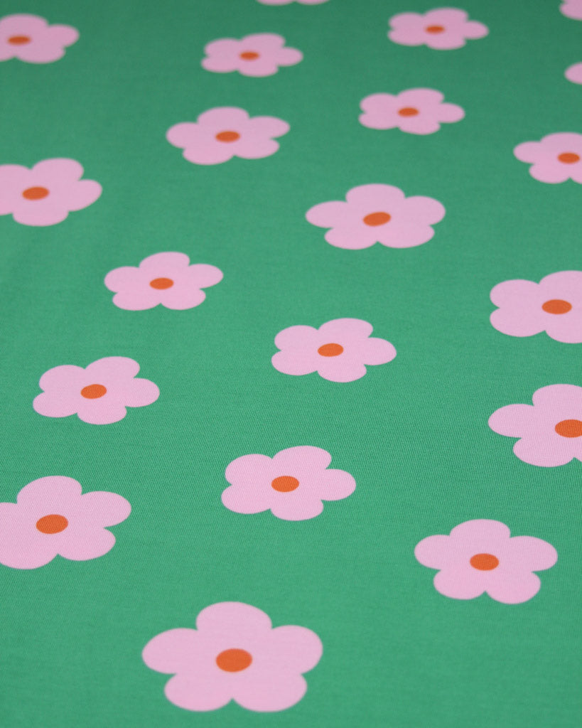 Pattern of pink flowers with orange centers on a green background