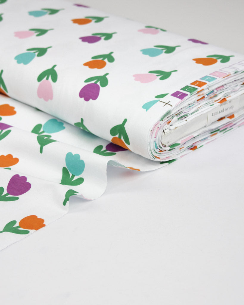 Roll of jersey fabric with colourful tulip pattern on a white background