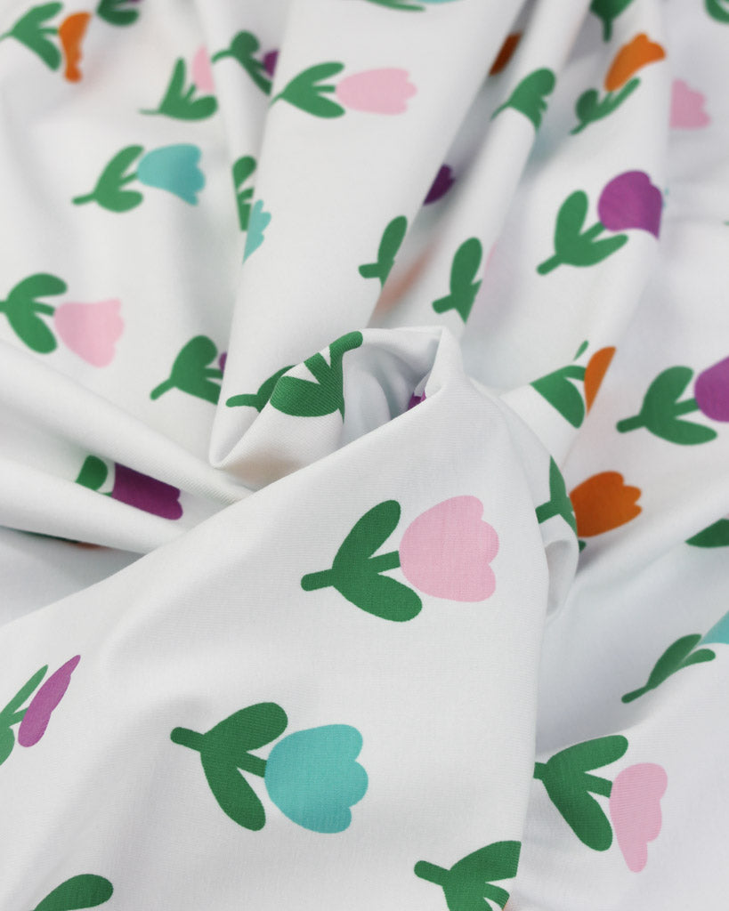 Stretch jersey fabric with colourful tulip floral pattern on a white background