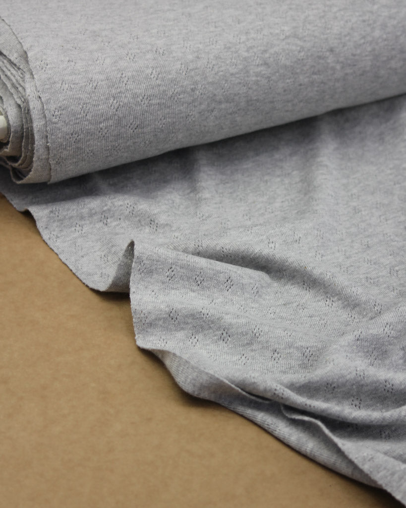 Roll of grey knit fabric on a brown surface