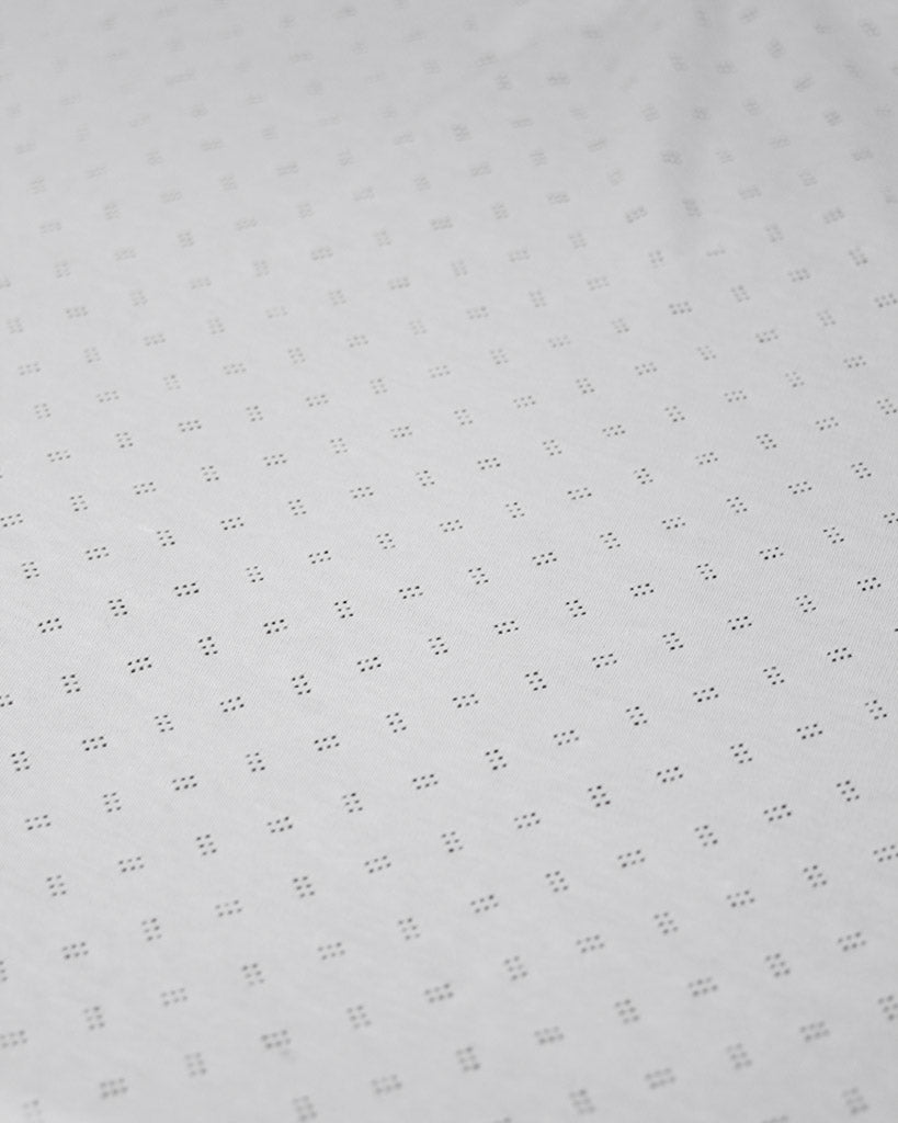White fabric with a subtle pointelle pattern on a white background