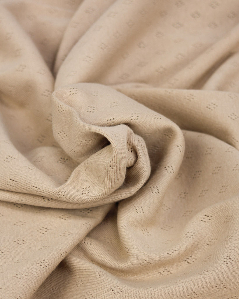 Close-up of beige pointelle fabric with a subtle pattern