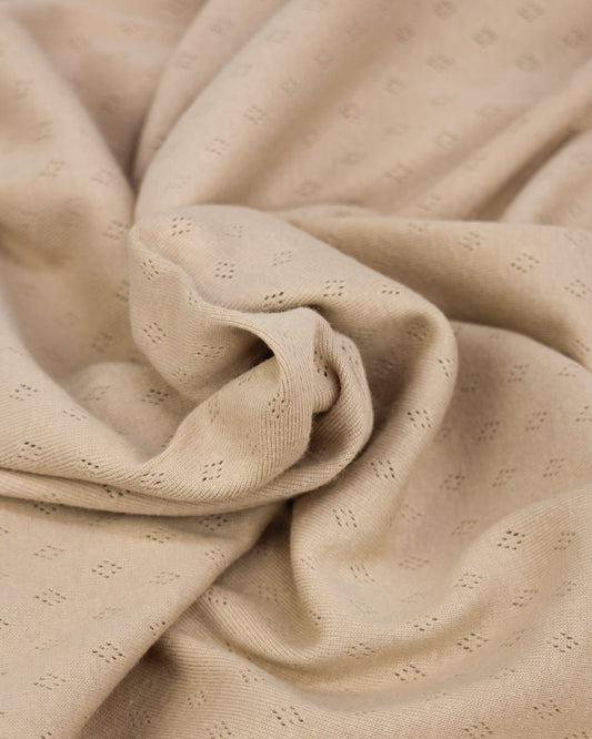 Close-up of beige pointelle fabric with a subtle pattern