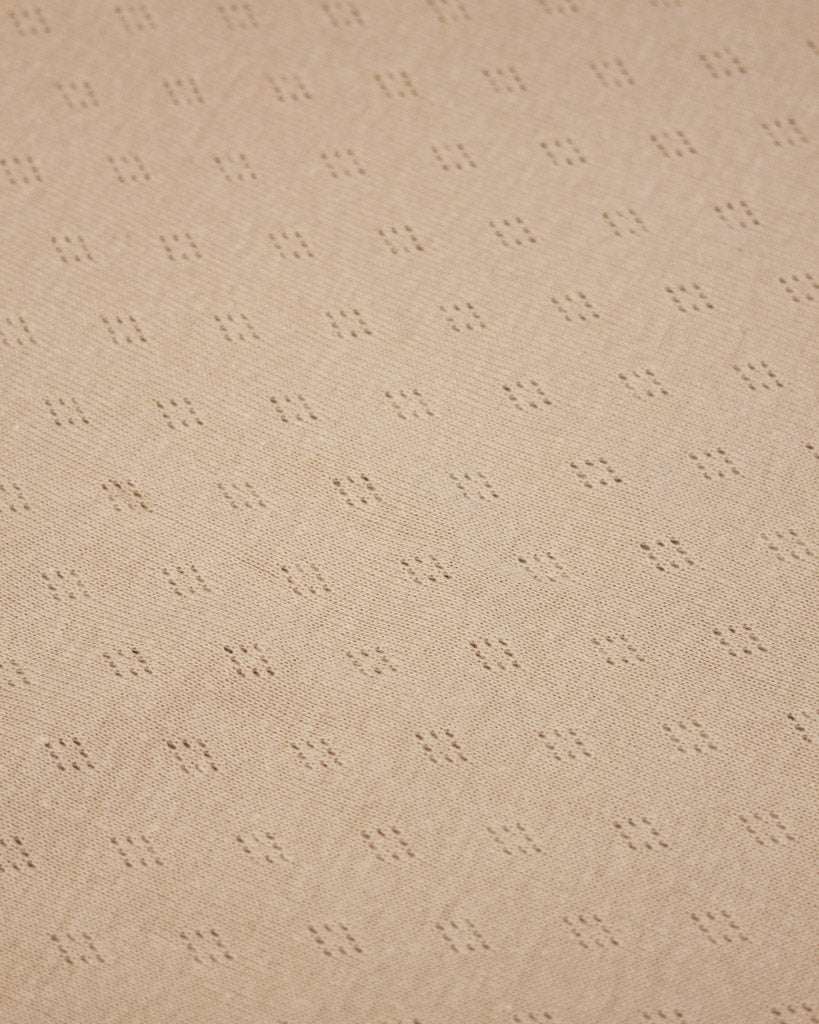 Beige pointelle knit fabric with a subtle diamond pattern