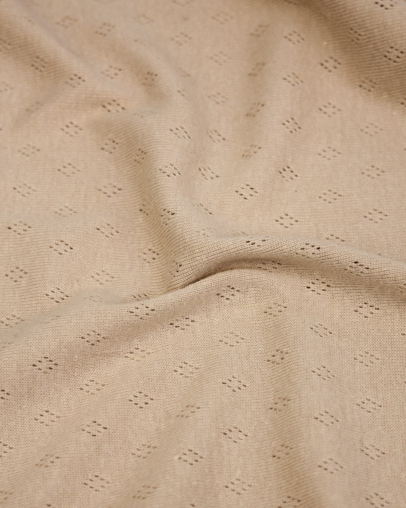 Close-up of beige pointelle fabric with a subtle pattern