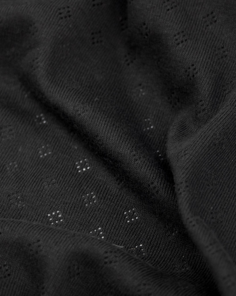 Close up of black fabric pointelle jersey fabric with small diamond hole patterns