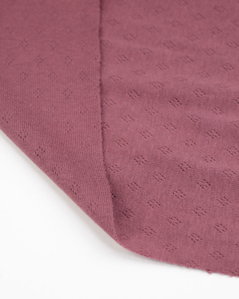 Close-up of a textured mulberry purple fabric corner on a white background
