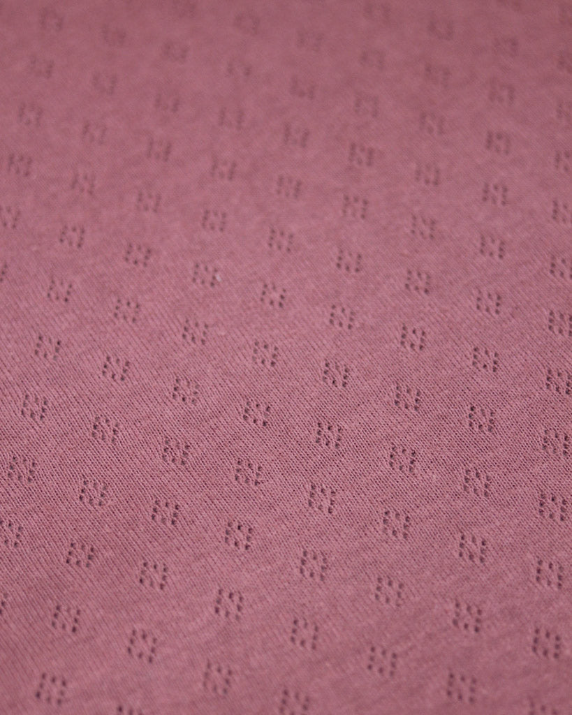 Close-up of a textured mulberry purple fabric with a subtle pattern