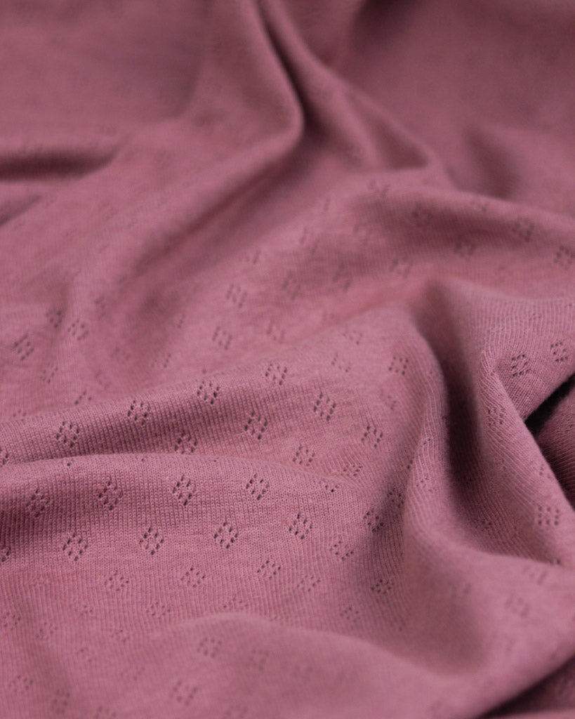 Close-up of mulberry pink textured pointelle fabric