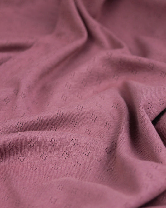 Close-up of mulberry pink textured pointelle fabric