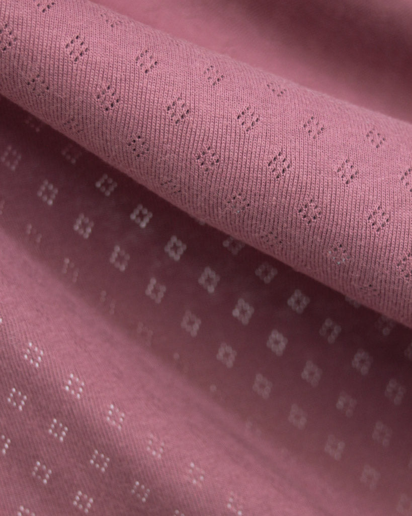 Close-up of mulberry pink pointelle fabric with a subtle pattern