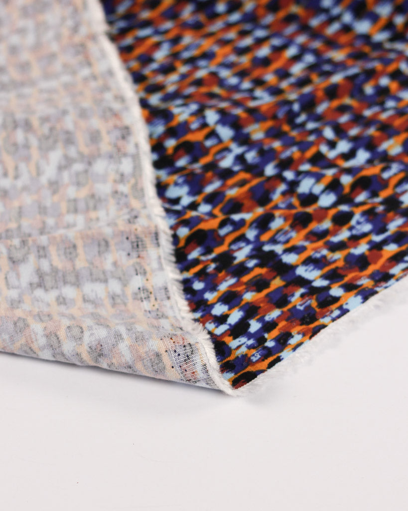 Close-up of a viscose twill fabric with a multicolor dot pattern on a white background