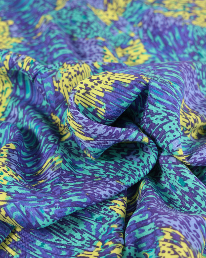 Close-up of colourful viscose lawn fabric with purple, blue, and yellow pattern