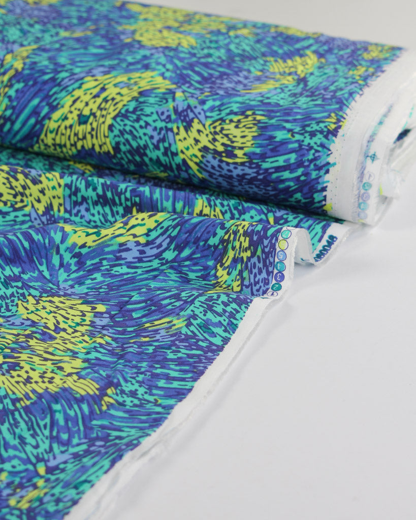 Roll of viscose fabric with blue and green abstract pattern on a white background