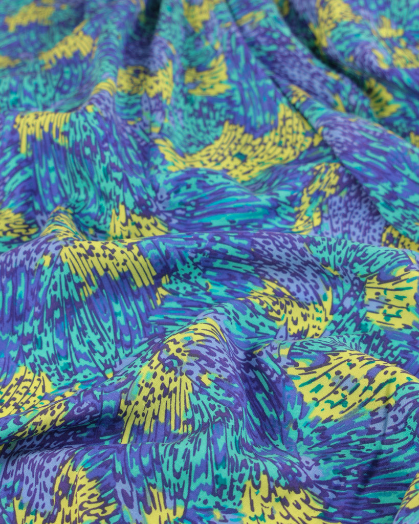 Close-up of viscose lawn fabric with blue, green, and yellow abstract pattern