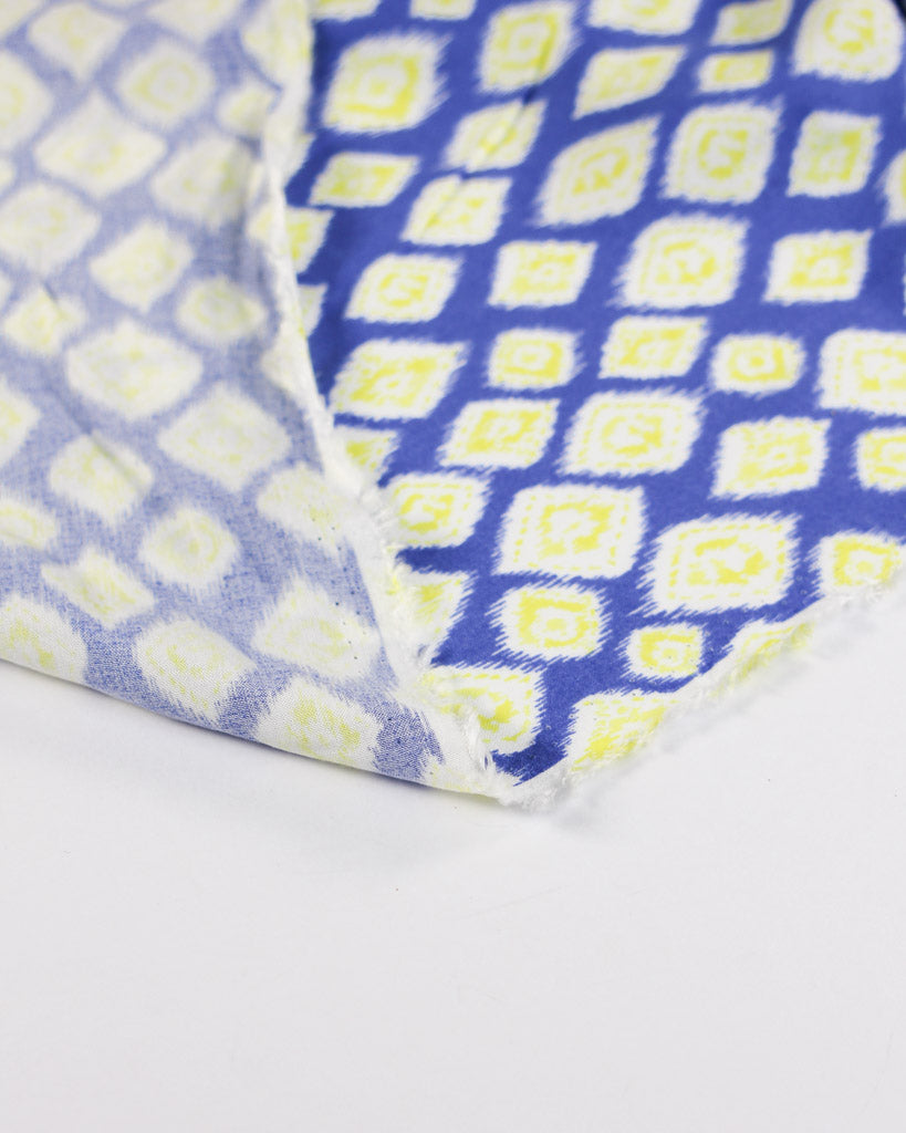 Close-up of a viscose lawn fabric with blue and yellow diamond pattern on a white background