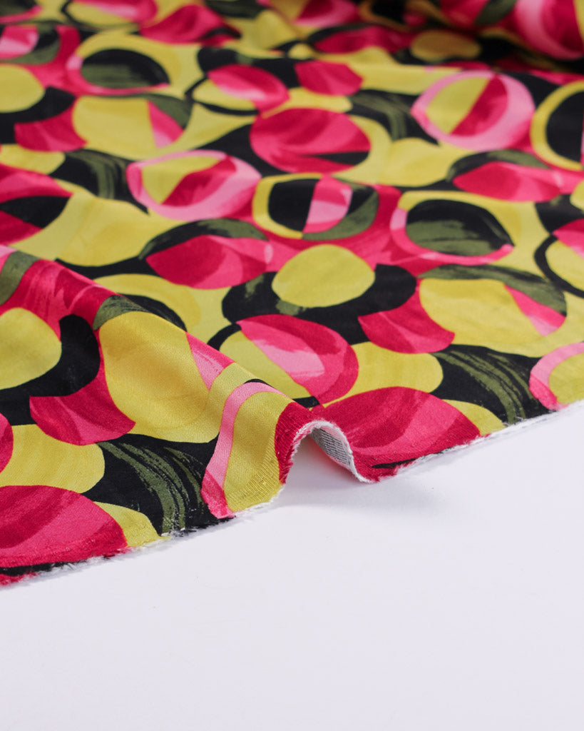 Colourful viscose satin fabric with pink, yellow, and black pattern on a white background