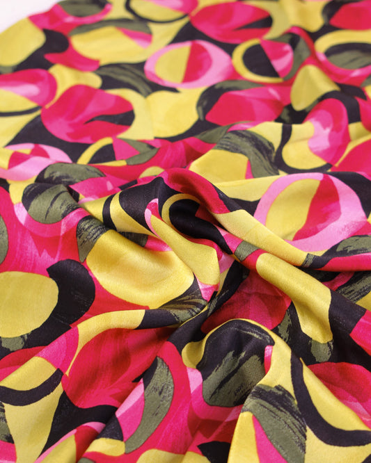 Colourful viscose satin fabric with abstract pattern in pink, yellow, and black.