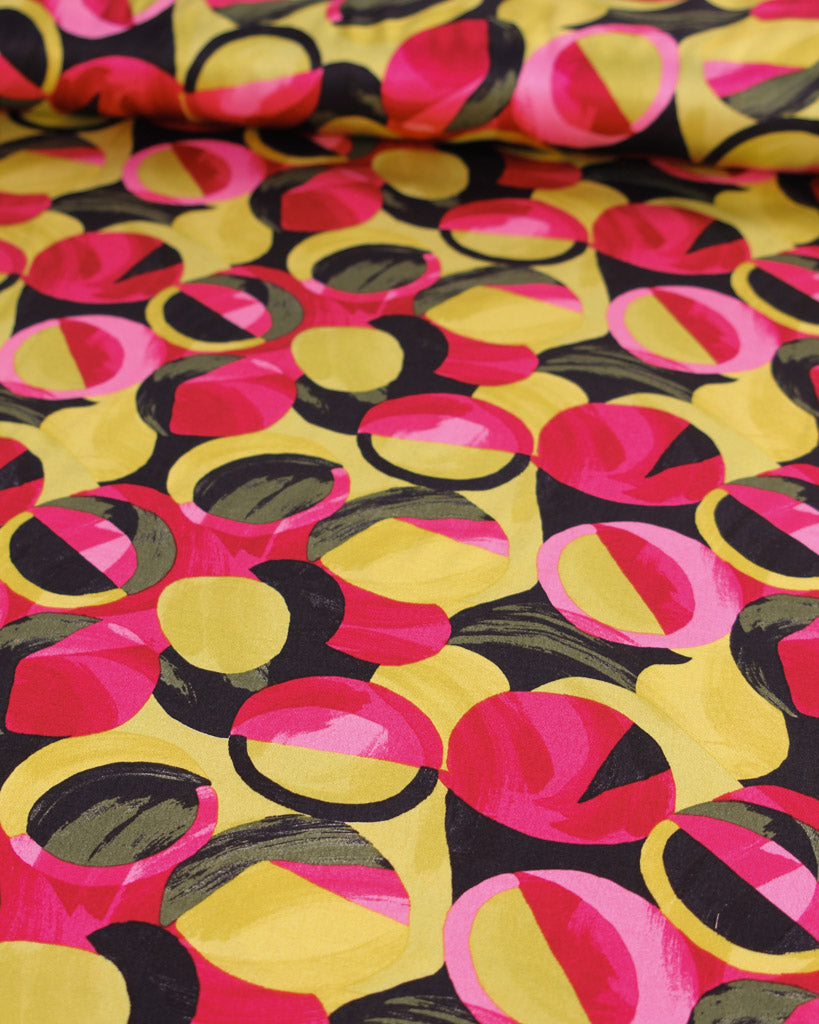 Colourful viscose fabric with geometric abstract pattern in pink, yellow, and black.
