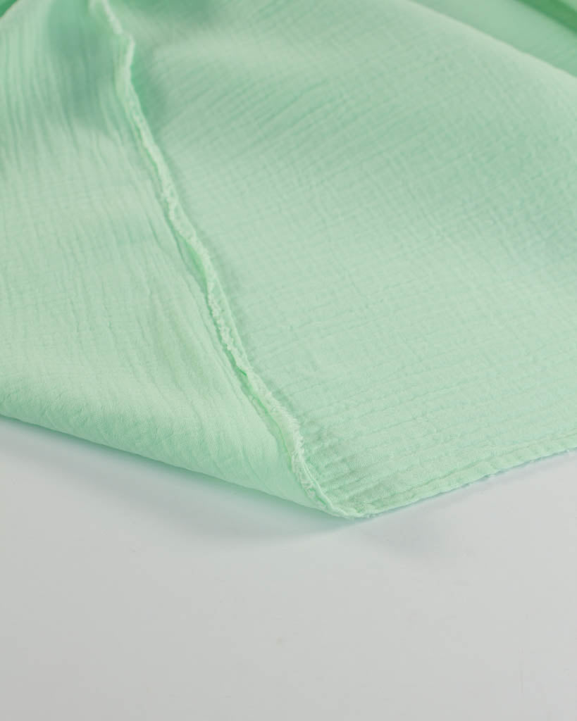 Close-up of a light mint green cotton double gauze fabric with a subtle texture