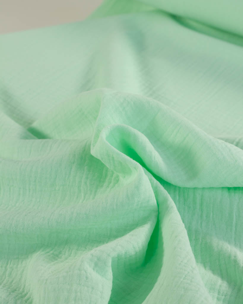 Close-up of mint green cotton double gauze fabric with a soft texture