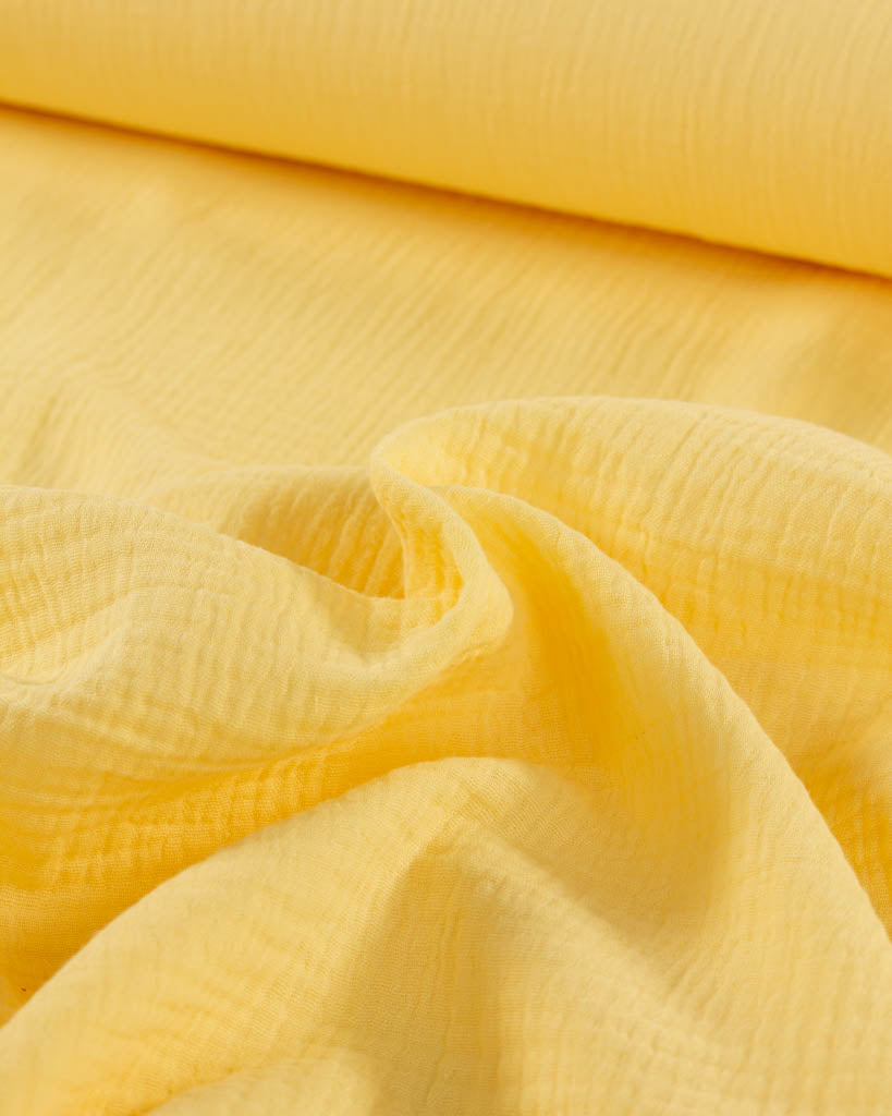 Close-up of banana yellow cotton double gauze fabric with a textured pattern