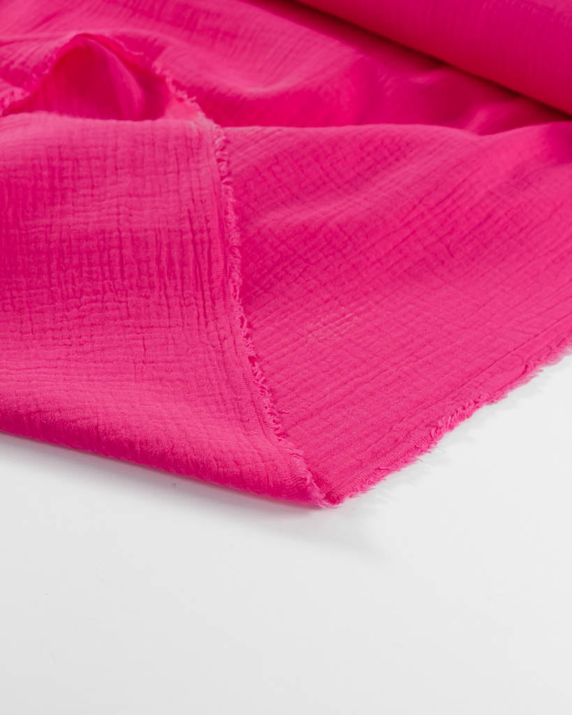 Close-up of bright pink cotton double gauze fabric on a white background