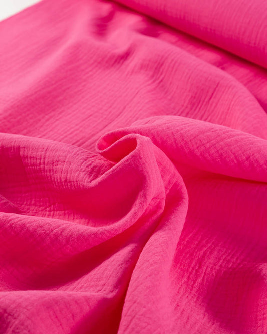 Close-up of hot pink cotton double gauze fabric with ruched texture