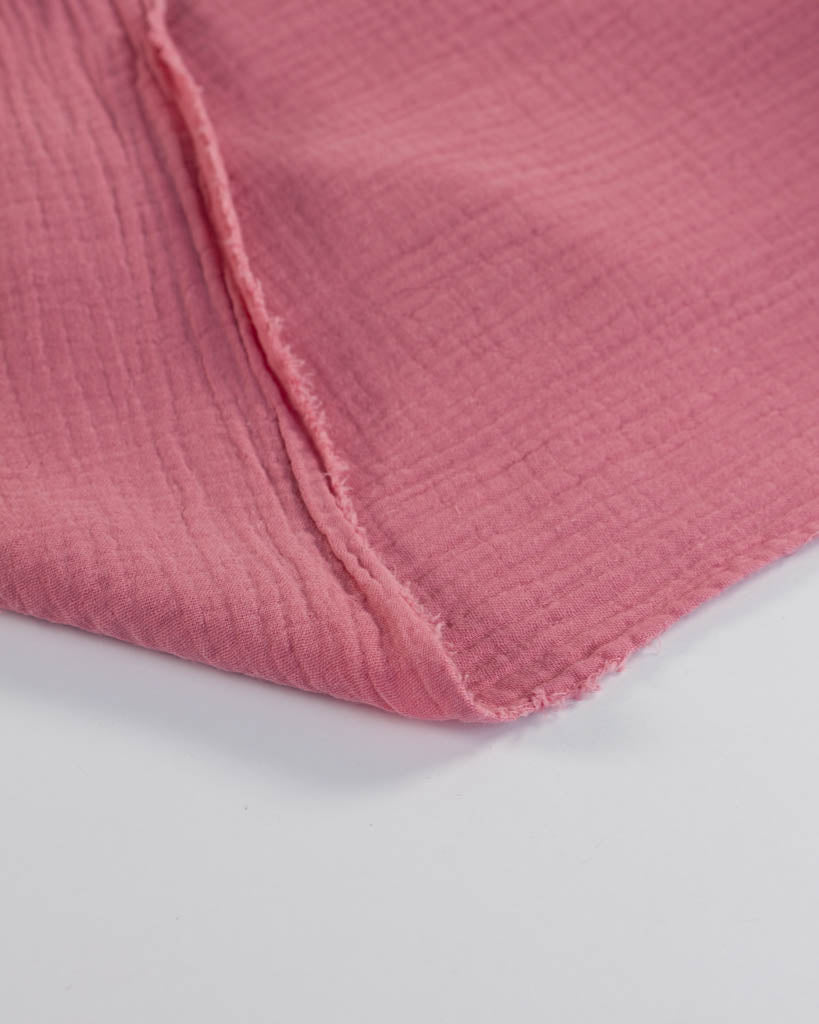Close-up of a pink textured cotton double gauze fabric on a white background
