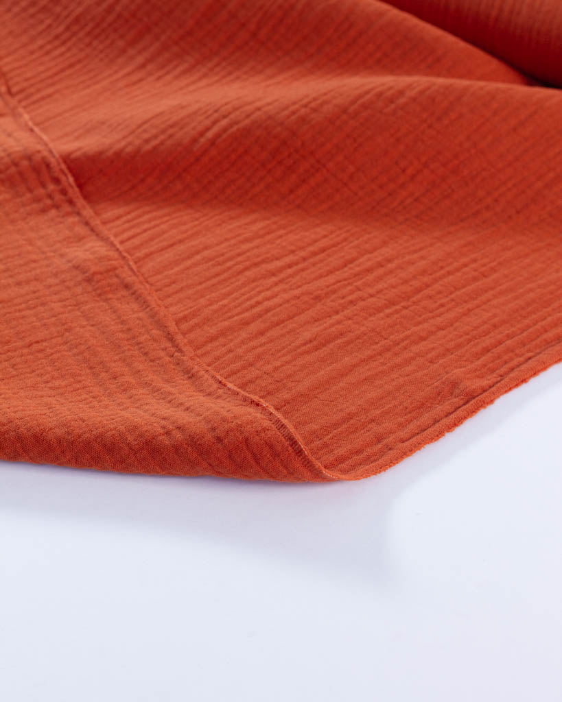 Close-up of orange cotton double gauze fabric on a white background